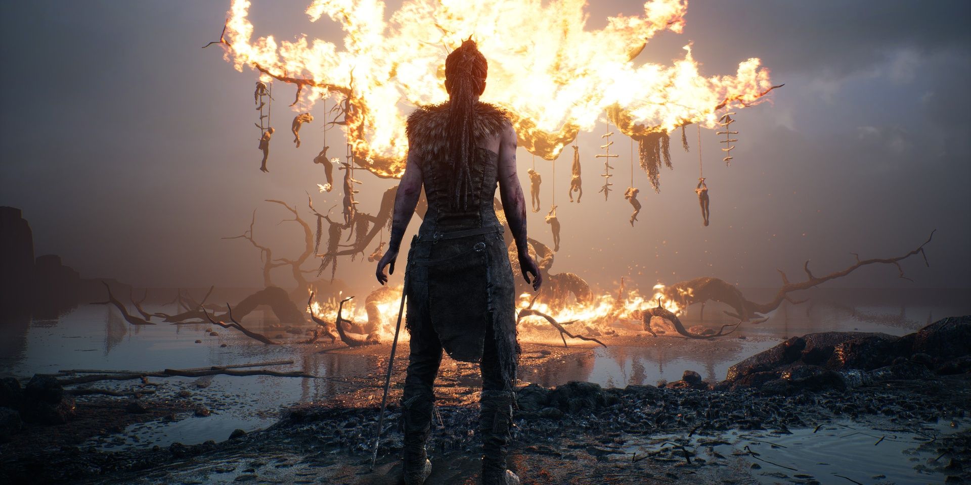 Hellblade Senua's Sacrifice, Senua watching as tree filled with hanging bodies burning down.